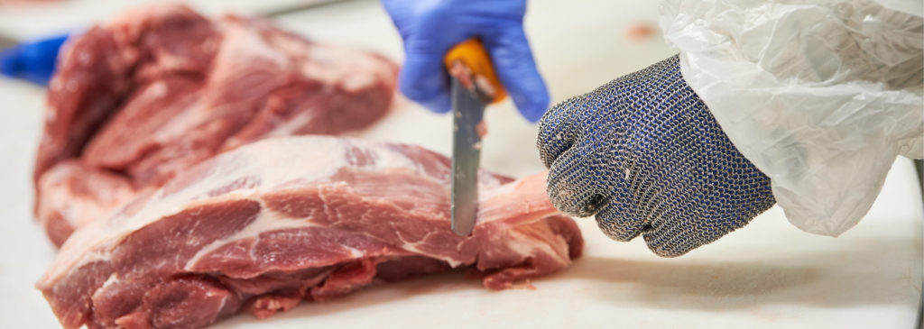 Raw slices of steak on a conveyor belt being evaluated before packaging.